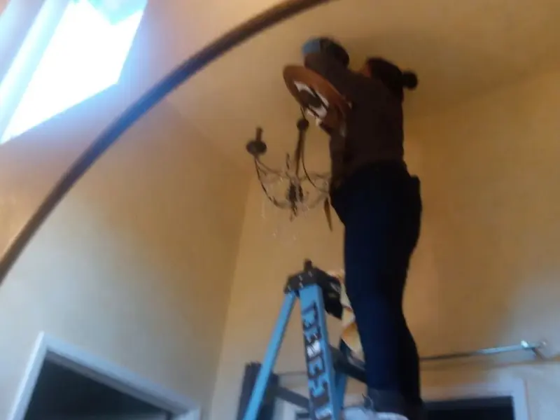 Electrician installing a chandelier in a Gladeview residence